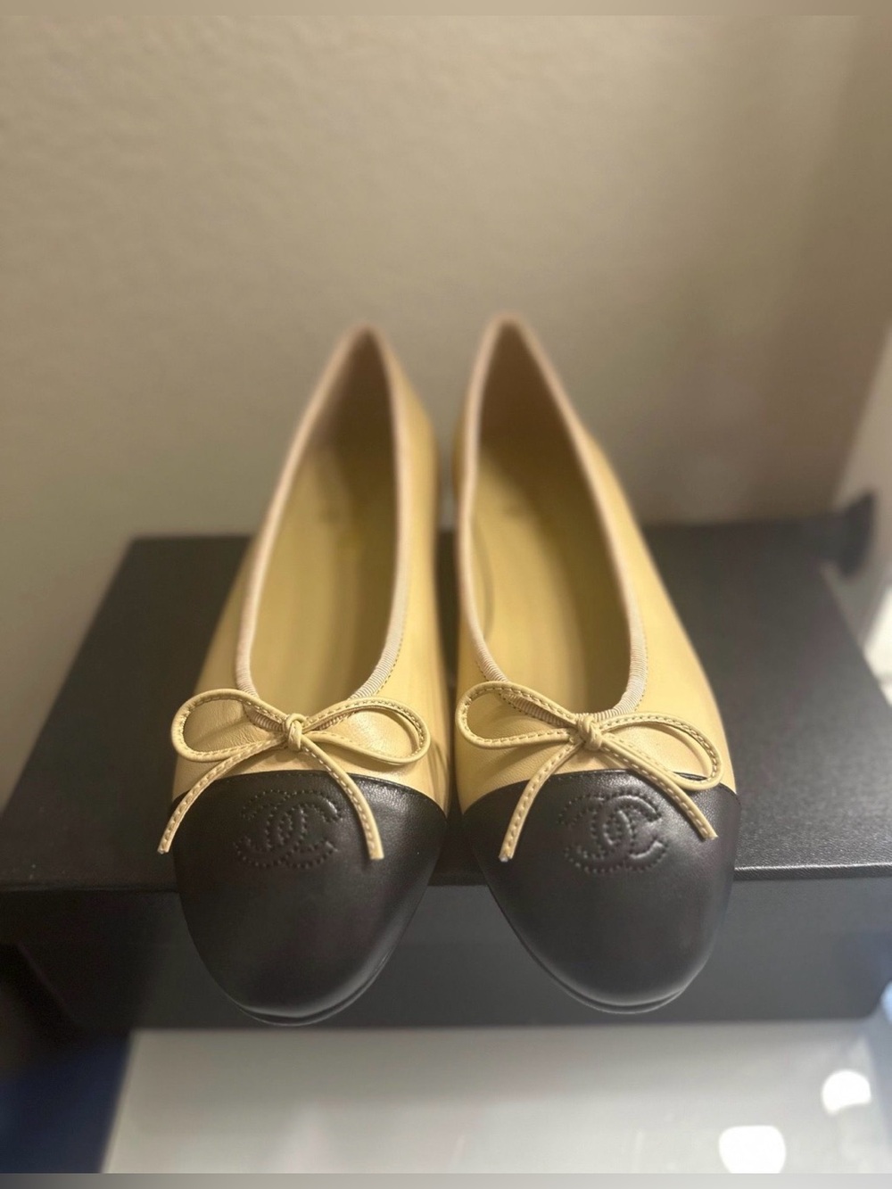Chanel ballet flats in beige lambskin body & black cap toe with CC logo.